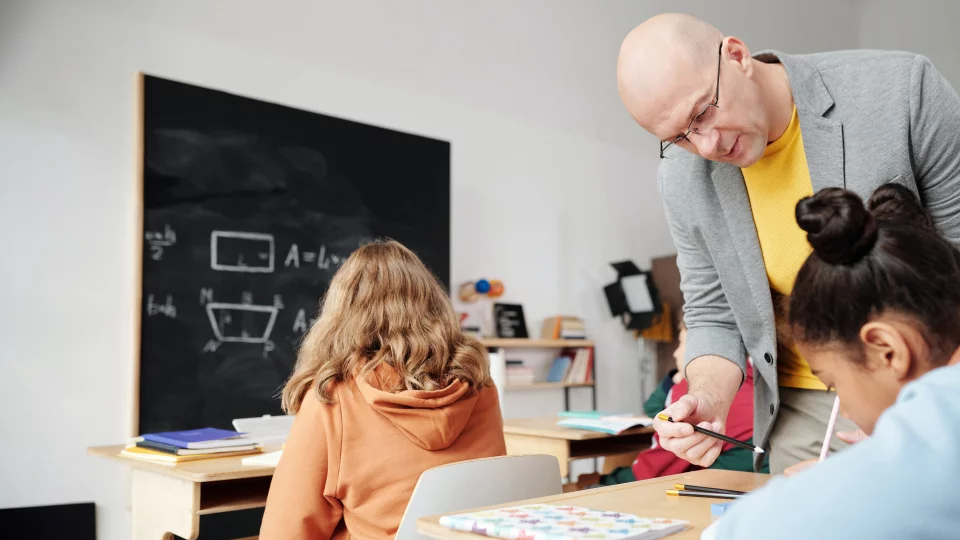 Lehrer assistiert Schülerin bei Aufgaben